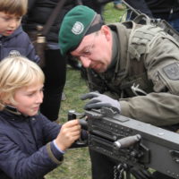 schenkt kindern kein kriegsspielzeug – lasst sie mit echten waffen spielen – 009 - kinder spielen mit kriegsgeraet und werden dabei von soldaten beraten.